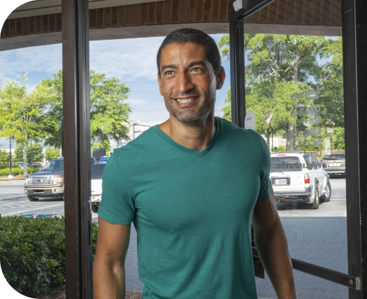 Image of a person smiling, standing outside a building, representing an in-branch payment option.